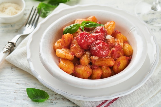 Gnocchi de pomme de terre Gnocchi traditionnel de pommes de terre fait maison avec sauce tomate basilic et fromage parmesan sur la table de cuisine sur un fond de table de cuisine gris clair Nourriture italienne traditionnelle Vue supérieure