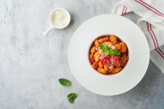 Gnocchis de pommes de terre Gnocchis de pommes de terre traditionnels faits maison avec sauce tomate basilic et parmesan sur table de cuisine sur fond de table de cuisine gris clair Cuisine italienne traditionnelle Vue de dessus