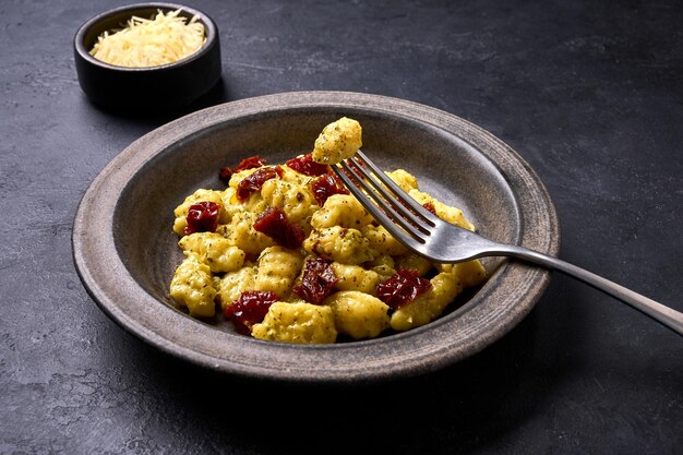 Gnocchis de pommes de terre italiens traditionnels piqués sur une fourchette allongée sur une assiette avec plat en gros plan sélectif