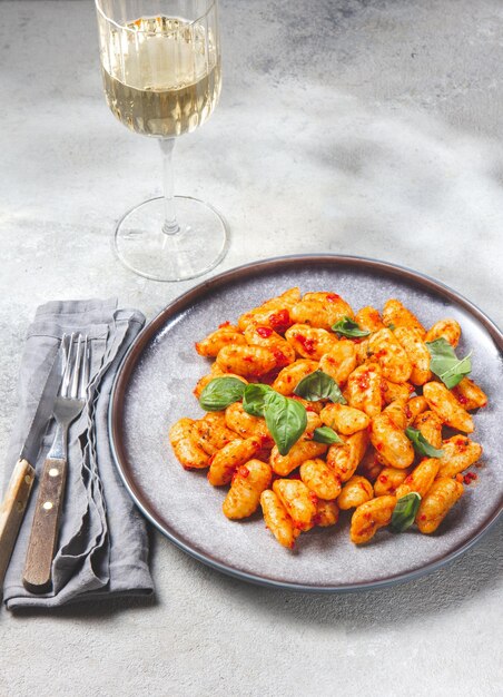 Gnocchis de pommes de terre italiens traditionnels avec sauce tomate et basilic frais sur fond gris marbré