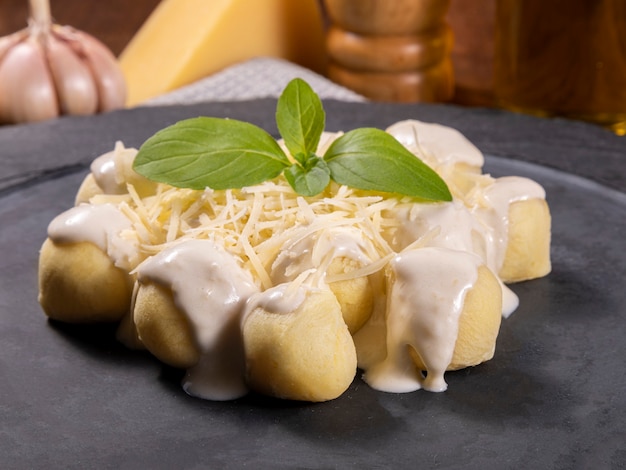 Gnocchis de pommes de terre à la sauce blanche avec du parmesan râpé et des feuilles de basilic.