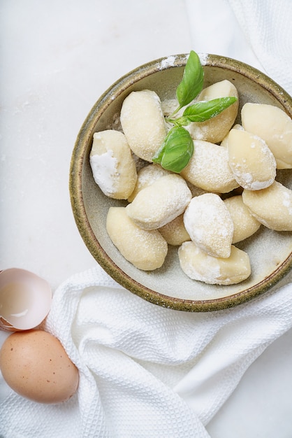 Gnocci de pommes de terre italiens traditionnels décorés de feuilles de basilic, œufs, farine. Vue de dessus. Mise à plat