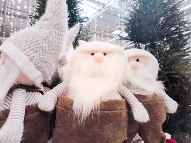 Des gnomes de Noël en peluche avec une barbe blanche se tiennent dans le hall du centre commercial sous le sapin de Noël