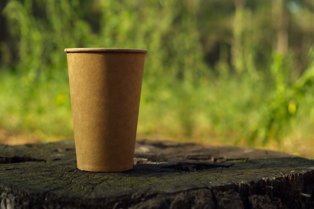 Gobelet en papier kraft brun sur une vieille souche dans les bois.