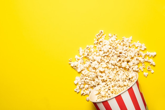 Gobelet en papier avec pop-corn sur fond jaune, place pour le texte.