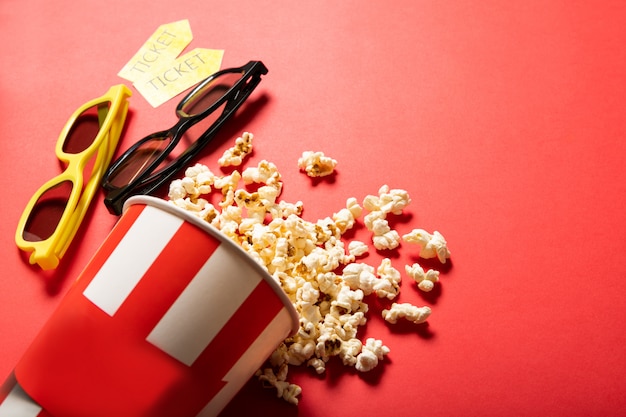 Gobelet en papier avec pop-corn sur fond rouge. Points et billets de cinéma