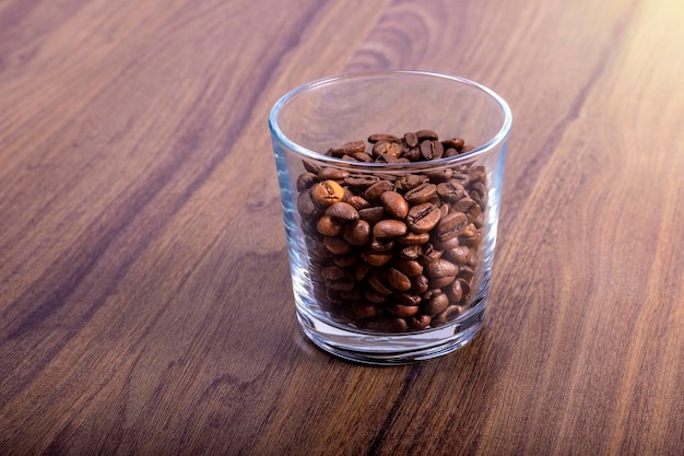 Gobelet en verre avec grains de café naturels sur table en bois de noyer Journée internationale du café 1er octobre