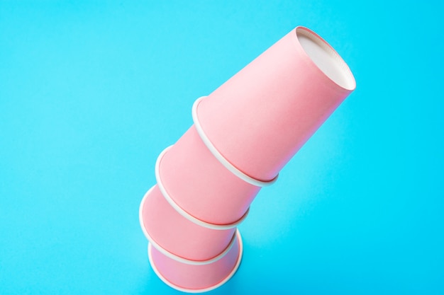 Gobelets en papier rose empilés sur fond bleu