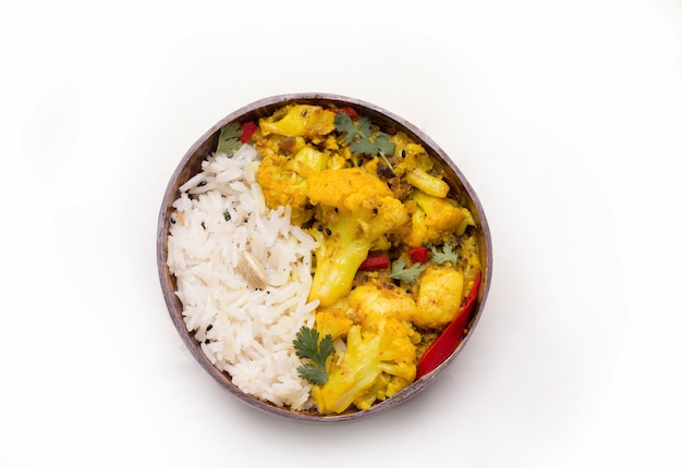 Gobi aloo plat végétarien indien traditionnel de chou-fleur dans une assiette avec du riz sur blanc