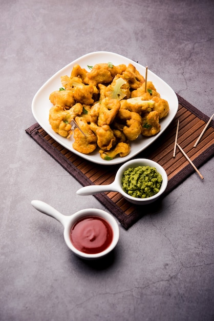 Gobi pakora ou Phoolgobi pakoda fait à partir de pâte de pois chiches fraîche trempée dans du chou-fleur puis frit dans l'huile. servi avec ketchup et chutney à la menthe. mise au point sélective