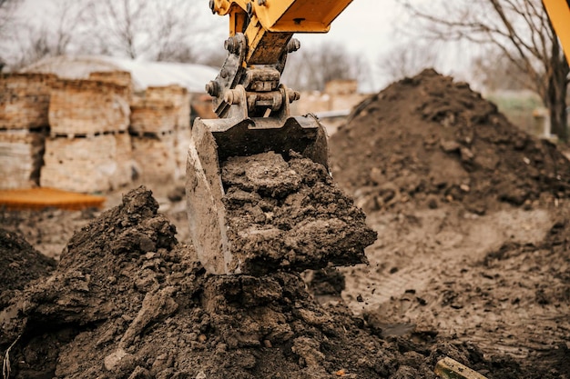 Un godet d'excavatrice renverse de la terre sur un tas sur un chantier de construction