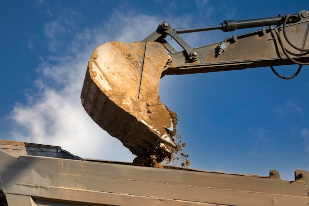 Le godet de l'excavatrice verse de la terre dans le camion