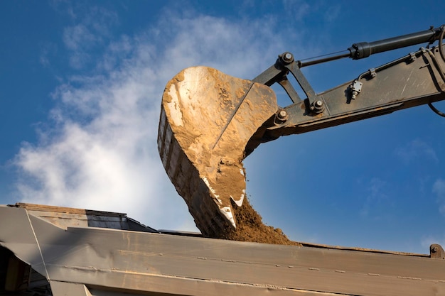 Le godet de l'excavatrice verse de la terre dans le camion