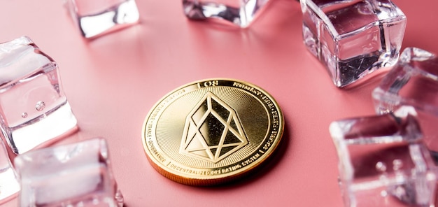 Photo golden eos cryptocurrency sur fond clair avec des glaçons