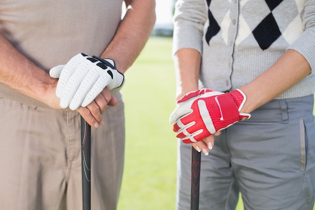 Golf couple debout et tenant des clubs