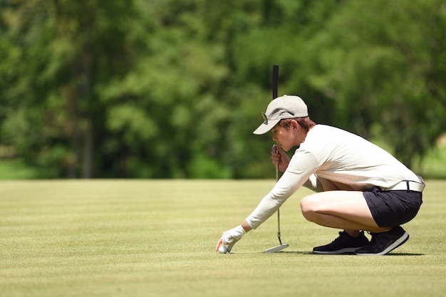 Golfeur femme vérifier la ligne pour mettre la balle de golf sur l'herbe verte