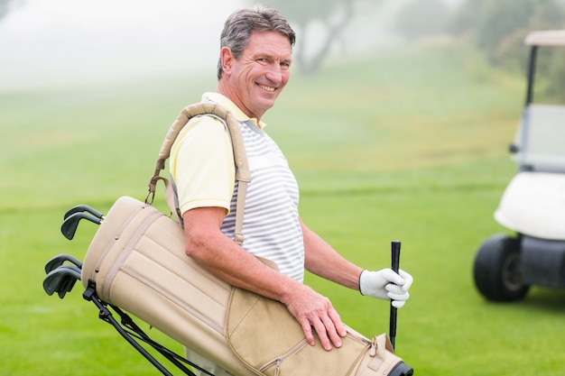 Golfeur heureux avec un buggy de golf derrière