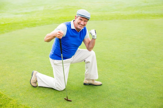 Golfeur souriant à genoux sur le green