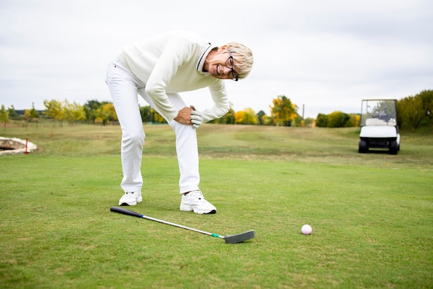 Golfeuse senior ayant des problèmes de santé et des douleurs au genou lors de l'entraînement au golf.