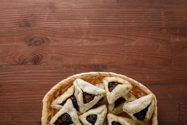 Gomentash aux graines de pavot et aux pruneaux fraîchement cuits pour les vacances de Pourim sur une table en bois dans un panier à paincopier l'espace photo horizontale