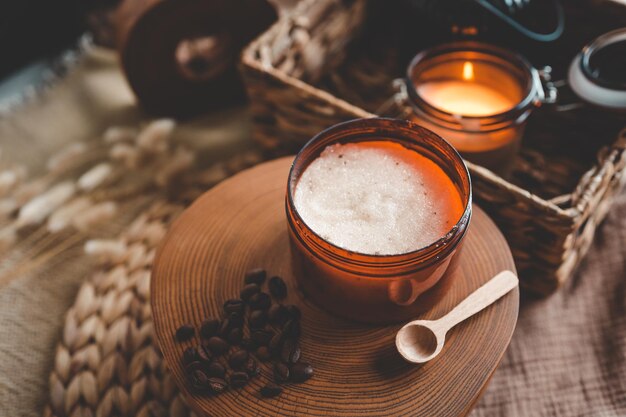 Gommage corporel de sucre de café moulu et d'huile de noix de coco dans un bocal en verre sur une table rustique blanche cosmétique maison pour le gommage et les soins de spa vue de dessus