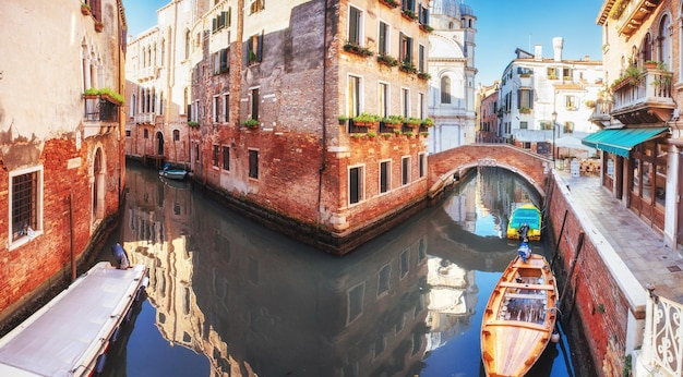 Gondoles traditionnelles sur un canal étroit entre des maisons historiques colorées à Venise, en Italie