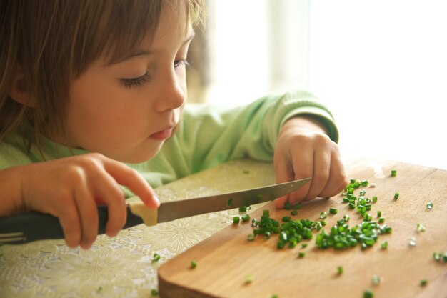 Gosse coupant l'oignon vert