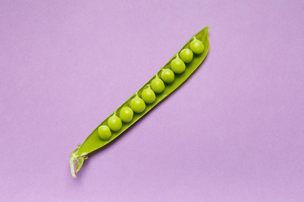 Photo gousse ouverte de pois verts frais avec des grains parfaits sur un fond lilas vue de dessus espace de copie protéines végétales produits sains