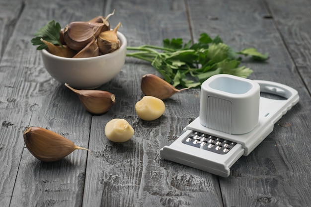 Gousses d'ail éparpillées, une râpe et un brin de persil sur une table en bois. Une épice populaire pour la cuisine.