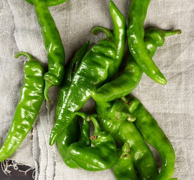 Gousses de piment vert sur une table en bois marron, vue du dessus