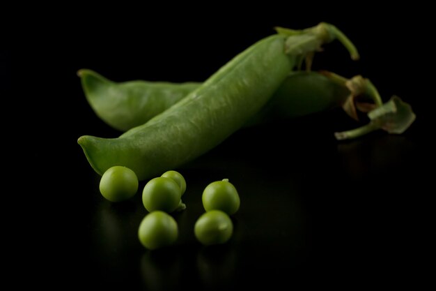 Gousses de pois sur fond noir, pois verts dans une cosse sur fond sombre