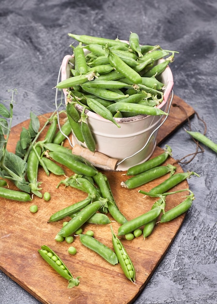 Gousses de pois verts avec des feuilles dans un bol