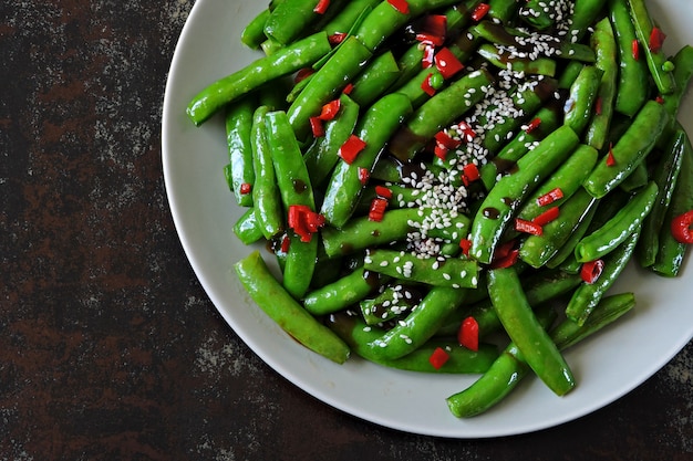 Gousses de pois verts avec piment et sésame. Gousses vertes à la chinoise.