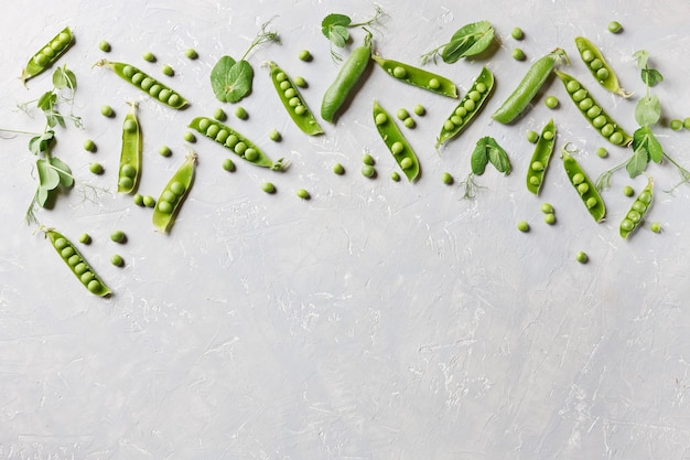 Gousses de pois verts et pois sur fond gris, vue de dessus