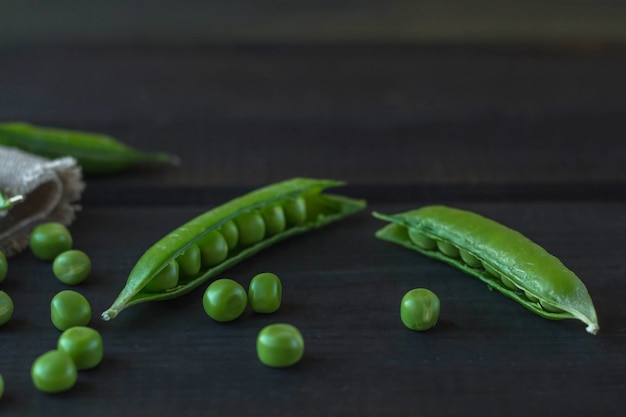 Gousses de pois verts et de pois sur une surface en bois sombre