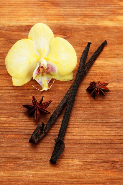 Photo gousses de vanille et anis avec fleur sur fond de bois marron