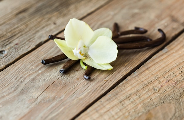 Photo gousses de vanille séchées et orchidée vanille sur table en bois