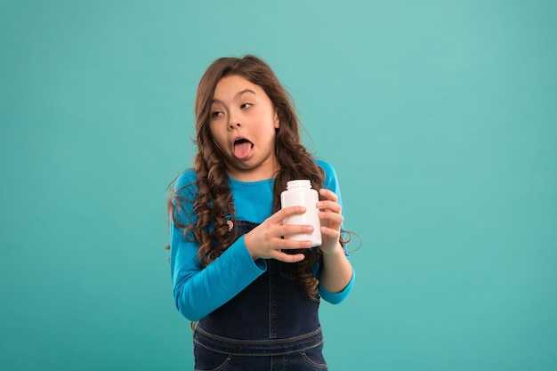 Goût dégoûtant. Soins de santé. Prenez des suppléments de vitamines. Une fille tient une bouteille de médicaments. Notion de vitamine. Besoin de suppléments vitaminiques. L'enfant prend des médicaments. Traitement et médecine. Épidémie de Coronavirus.