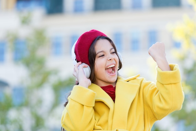 Goût musical chez les adolescentes Petite fille écoutant de la musique profiter de sa chanson préférée Fille avec un casque Contexte urbain Passer la piste Groupe préféré Influence de la musique Enfant fille tenue d'automne appréciant la musique