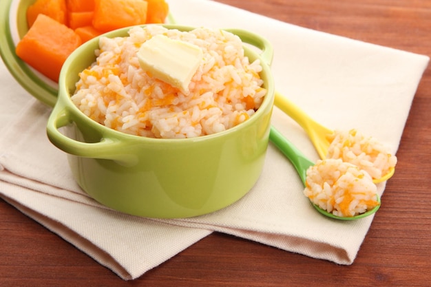 Goûtez la bouillie de riz avec de la citrouille dans des casseroles sur fond de bois