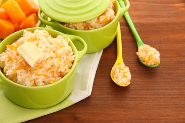 Goûtez la bouillie de riz avec de la citrouille dans des casseroles sur fond de bois