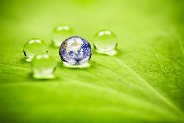 Une goutte d'eau avec la planète dessus est entourée de gouttelettes d'eau.