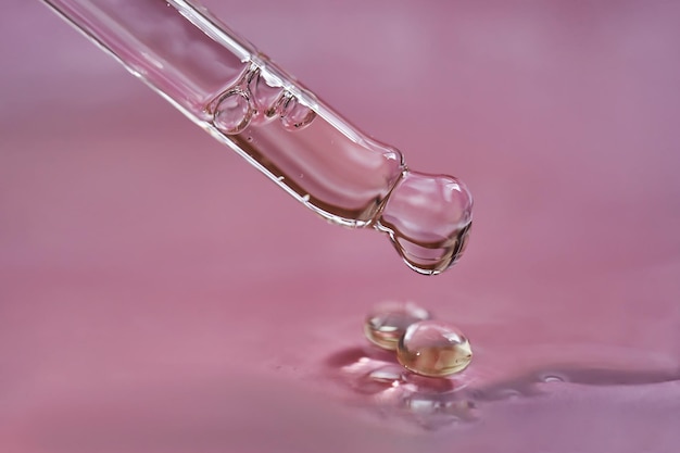 goutte-à-goutte avec sérum ou huile cosmétique sur fond rose