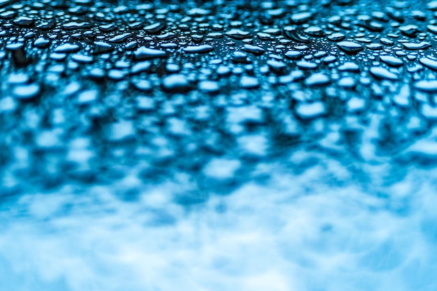 Gouttelettes d'eau bleues réalistes condensées pour un design créatif sur un verre Gouttes d'eau claires de forme différente ci-dessus sur la photo et floues ci-dessousMacro shot