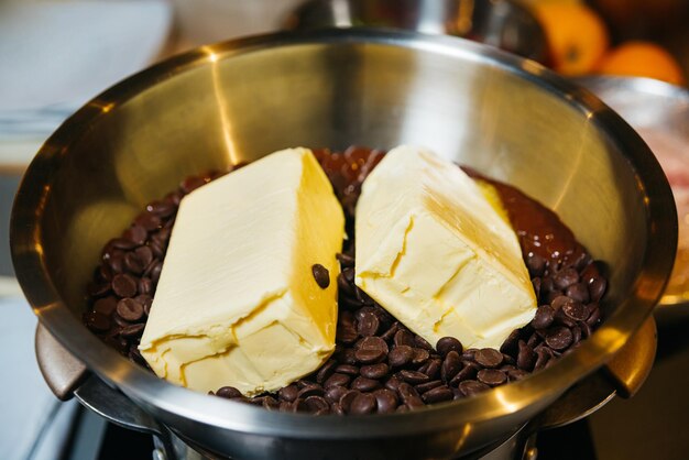 Photo gouttes de chocolat avec du beurre dans un bol en métal prêtes à être fondues ingrédients pour faire un dessert