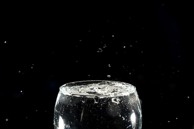 Photo des gouttes d'eau éclaboussées dans une coupe de verre pleine effet éclabousse