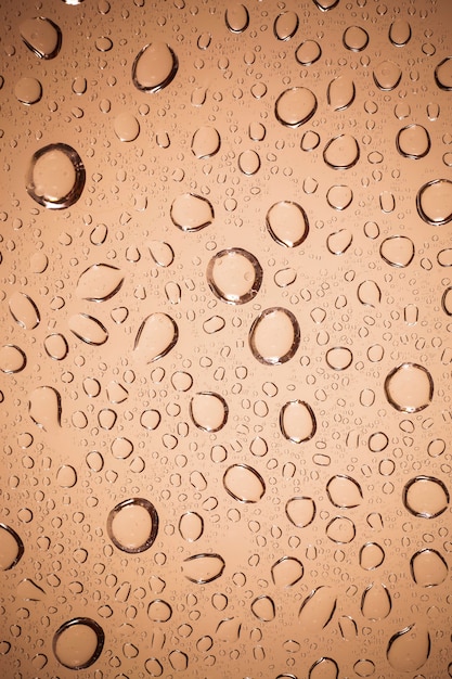 Gouttes d'eau sur fond de verre marron.