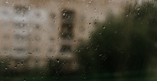 Gouttes d'eau de pluie sur le verre. gouttes collectées sur la fenêtre dans le contexte de bâtiments à plusieurs étages.