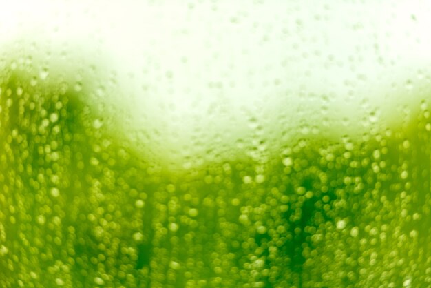 Photo gouttes d'eau sur une surface en verre. image flou vert défocalisé avec bokeh