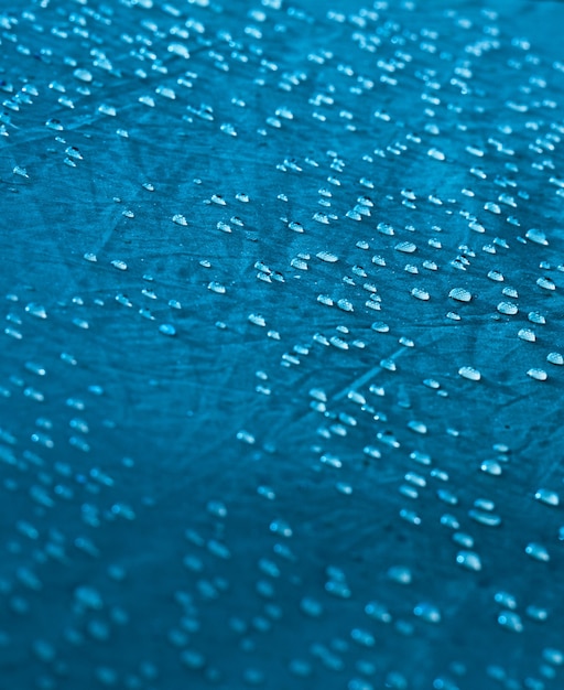 Gouttes d'eau sur le tissu de la membrane imperméable. Vue détaillée de la texture du tissu imperméable synthétique bleu. Rosée du matin sur tente.